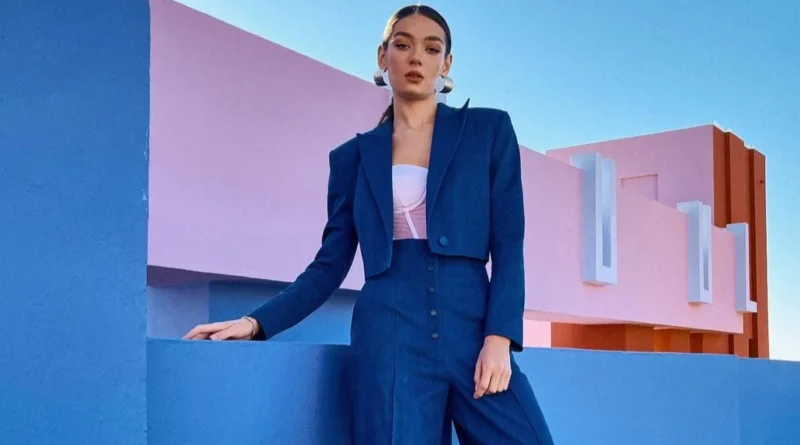 Жінка-модель позує на фоні міста у синьому костюмі