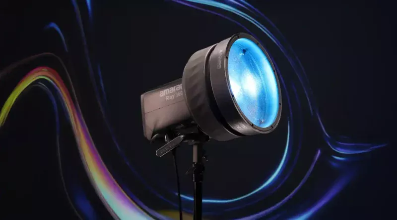 Освітлювальний прилад Amaran Ray 360c зі світним блакитним рефлектором на штативі, на темному тлі з різнокольоровими світловими лініями