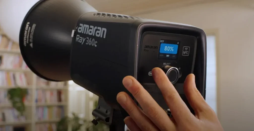 Великий план панелі керування Amaran Ray 360c: дисплей з яскравістю 80%, регулятор SELECT, індикатори NFC та Bluetooth